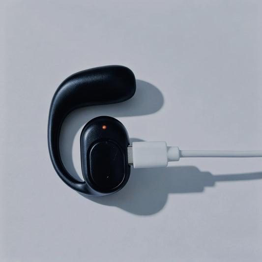 bone conduction bluetooth headset connected to a charger showing a red charging indicator light